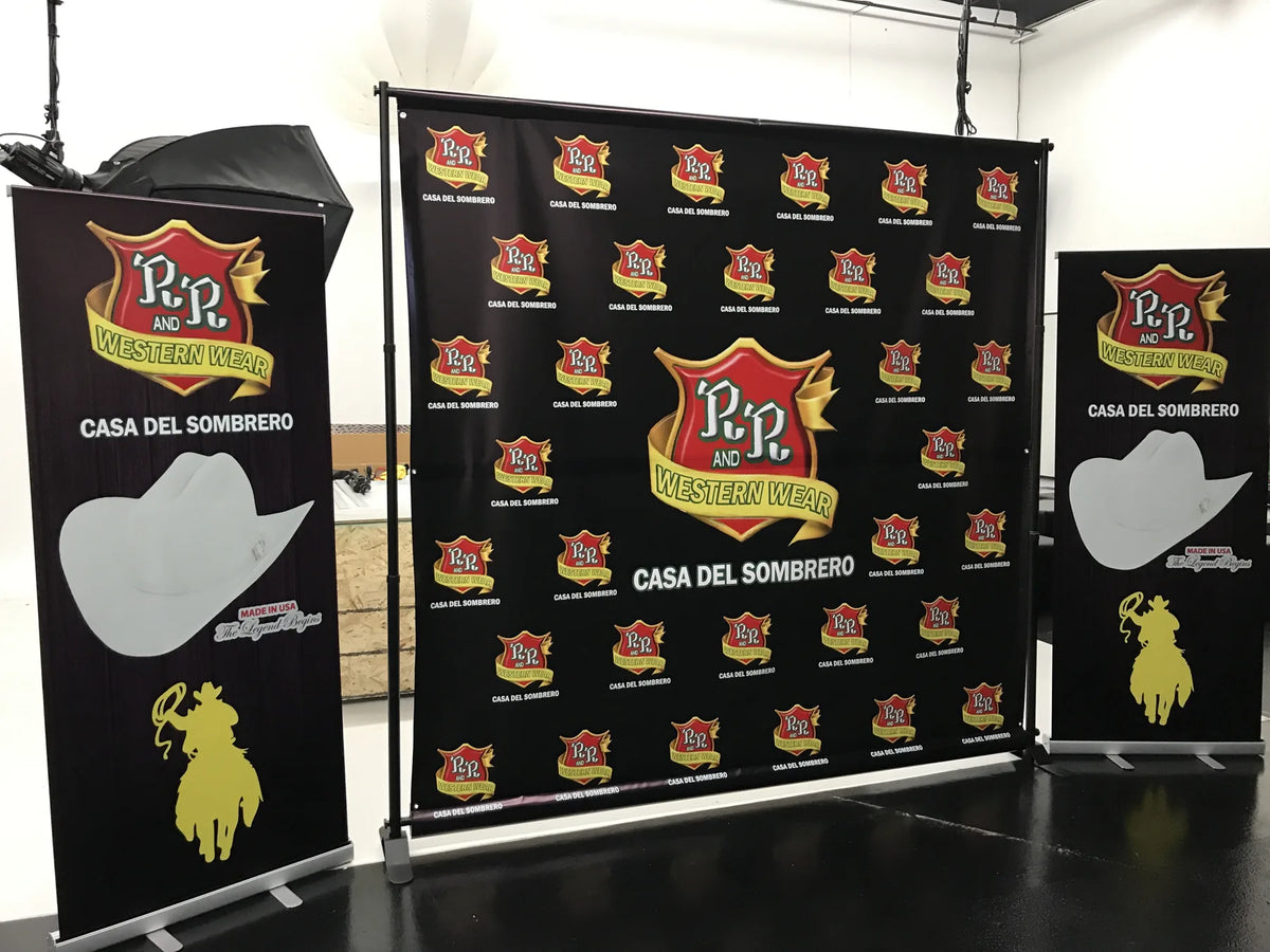 8' x 8' R&R Western Wear step-and-repeat backdrop with frame next to two matching roll-up banners printed in South Gate, CA