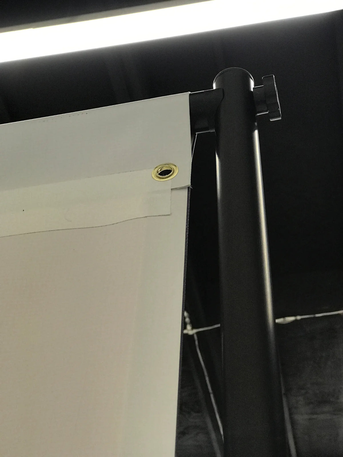 Detail of a grommet on a custom backdrop banner attached to the black adjustable backdrop frame at Urban Tee LLC