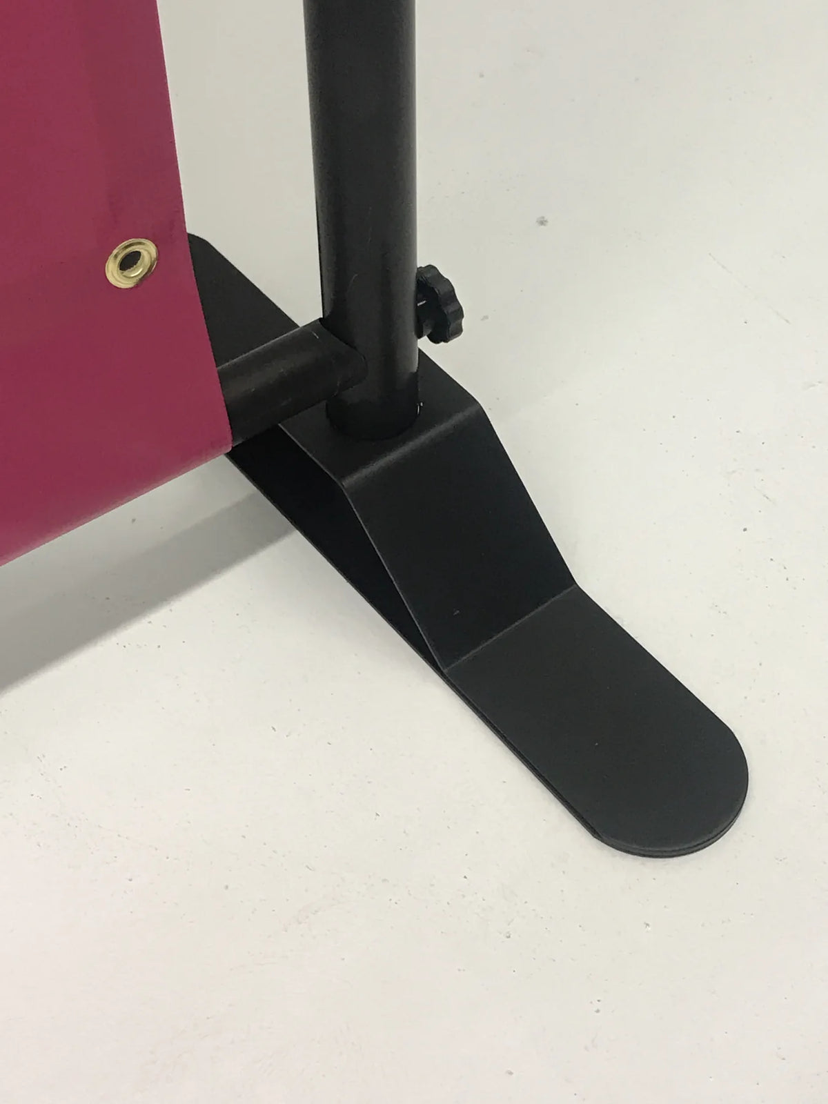 Close-up of the black adjustable stand base holding a pink 8' x 8' backdrop banner at Urban Tee LLC in South Gate, CA