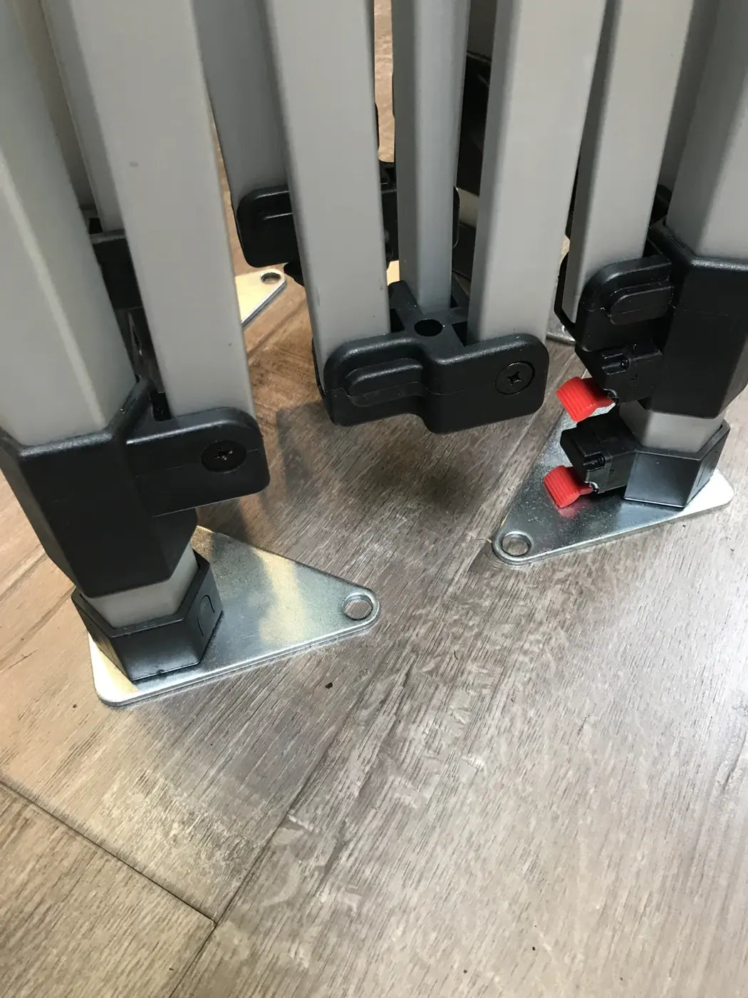 Folded canopy frame legs with metal base plates and red locking pins