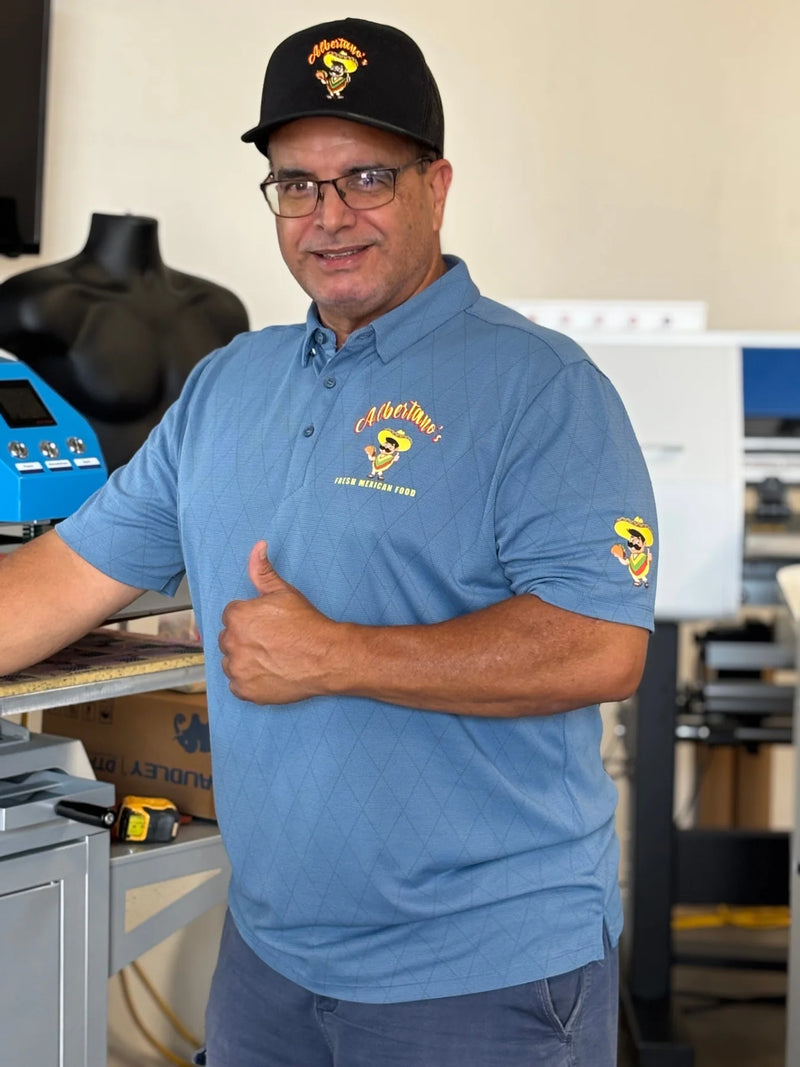 Business owner in a blue custom branded polo work uniform giving a thumbs up inside the South Gate print shop