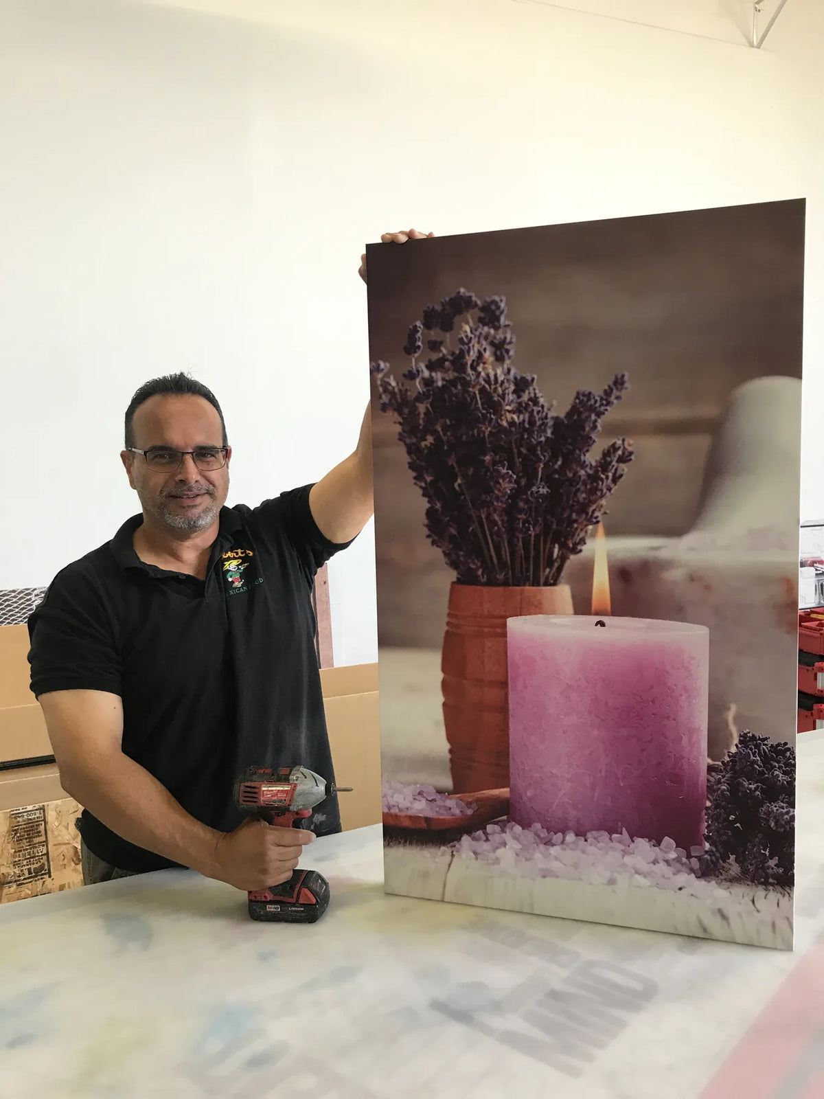 Urban Tee LLC team member holding a custom laminated vinyl print mounted on a rigid panel in South Gate, CA