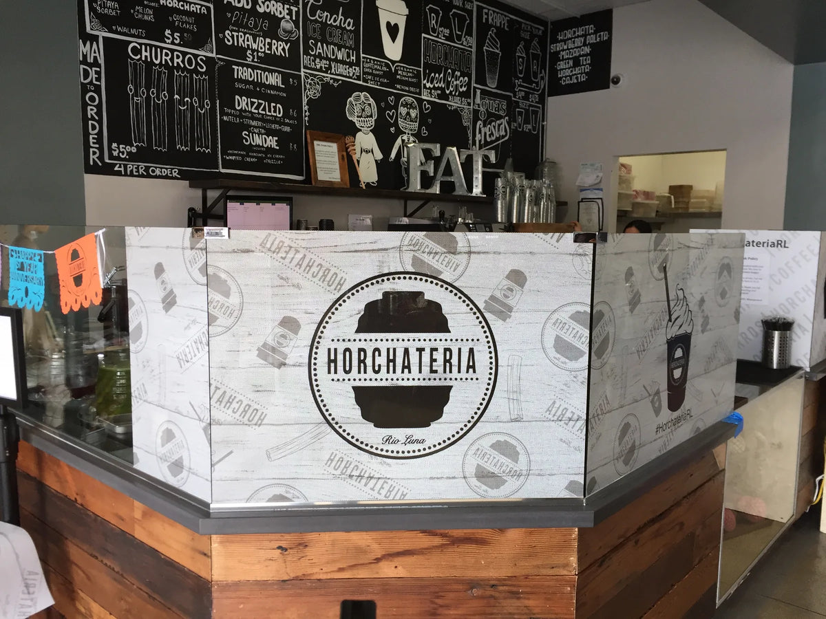 Perforated window film with Horchateria branding on a restaurant counter glass partition in the Los Angeles area