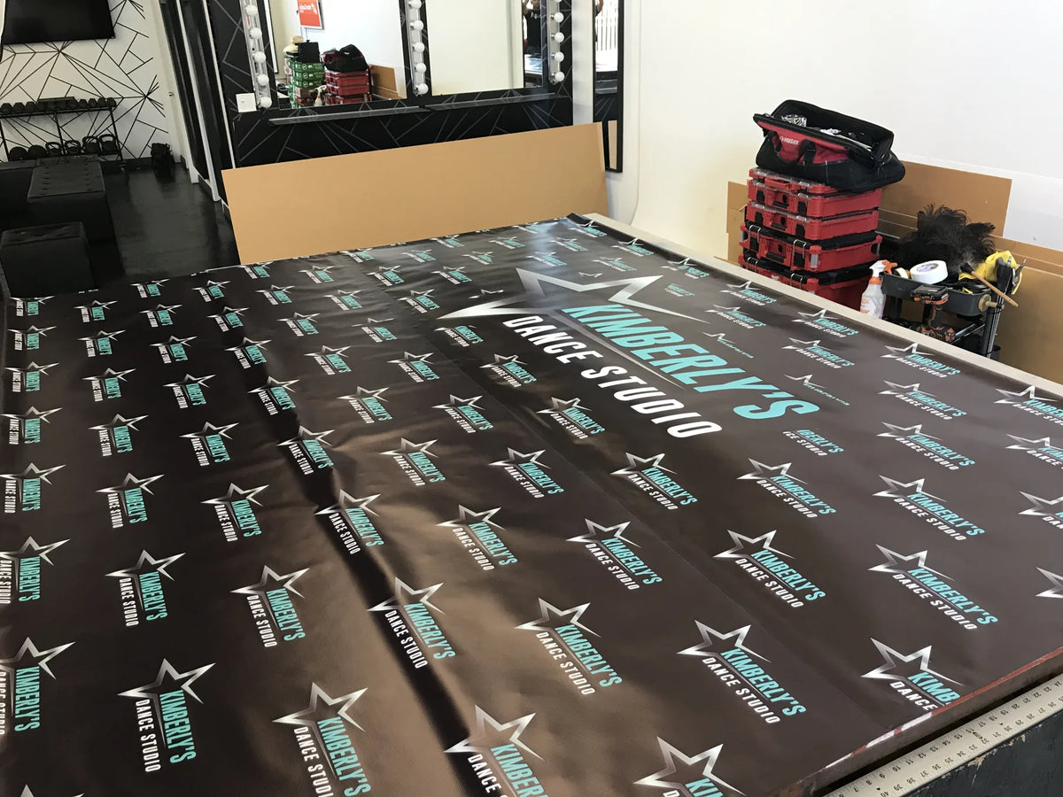 Full color Kimberly's Dance Studio step-and-repeat backdrop laid out on the cutting table at Urban Tee LLC in South Gate, CA